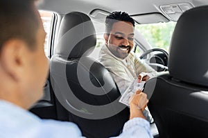 passenger giving money to smiling taxi car driver