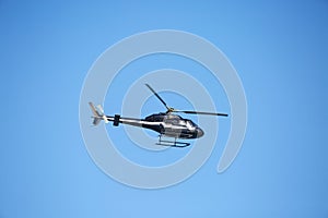 A passenger helicopter is flying against a clear blue sky.