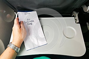 Passenger holding air sickness vomit bag in airplane