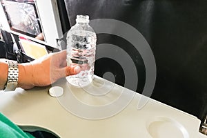 Passenger holding mineral water bottle in aeroplane cabin to drink