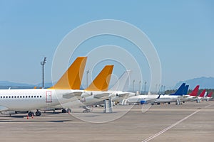 Passenger jets lined up in parking lots, tails view