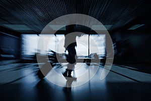 Passenger with luggage walking along an airport departure lounge, motion blur