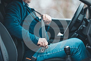 Passenger man fastening seat belt in the car, transport and safety concept
