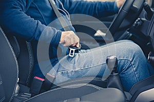 Passenger man fastening seat belt in the car, transport and safety concept