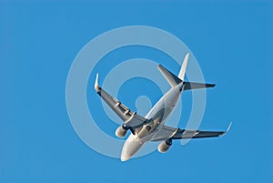 Passenger plane in a clean blue sky, bottom view.