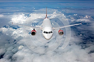 Passenger plane flies high above the clouds. Front view