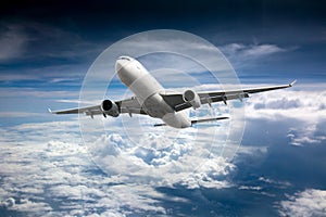 Passenger plane flies high in the blue sky above the clouds. Front view