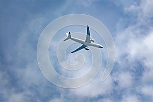 Passenger plane flies in the sky, bottom view.