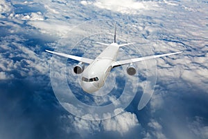 Passenger plane in flight. Aircraft flies high in the sky above the clouds. Front view of airplane