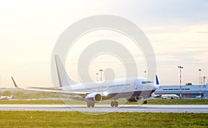 Passenger plane fly up over take-off runway from airport at sunset