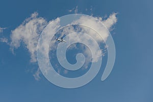 passenger plane is flying against the background of a blue sky with clouds