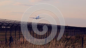 The passenger plane jet taking off over safety airport fence at sunset