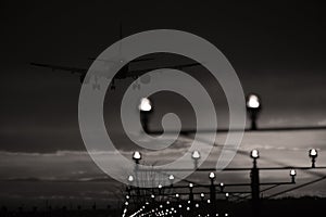 Silhouette of plane landing, runway lights, blue effect