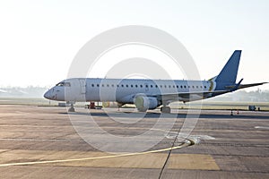 Passenger plane on a long parking lot in a small airport, morning light.