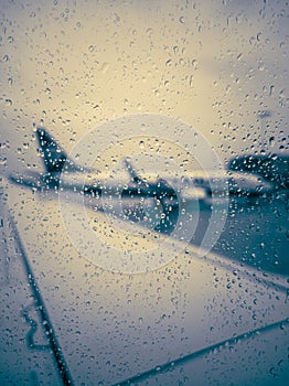 A passenger plane stands at the airport, view from the plane window during the rain