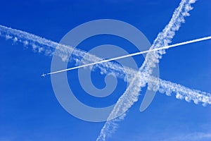 a passenger plane with vapour trails in the blue sky