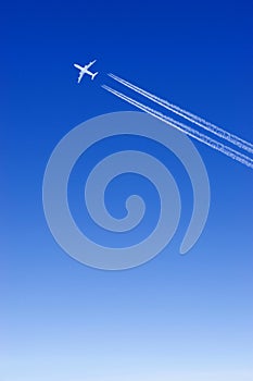 a passenger plane with vapour trails in the blue sky