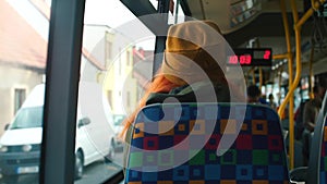 The passenger of a public transport bus looks out the window.