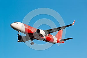 Passenger red and white colours airplane landing gear flying in the clear blue sky