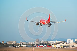 Passenger red and white colours airplane landing at local airport in the clear blue sky