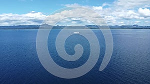 a passenger ship sails on the sea against the backdrop of mountains, aerial view