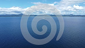 a passenger ship sails on the sea against the backdrop of mountains, aerial view