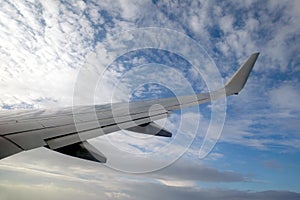 Passenger supersonic plane wing high moving from right to left in blue sky with clouds