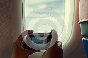 Passenger take a photo graph the beautiful view from porthole of airplane on sky with clouds under sun light