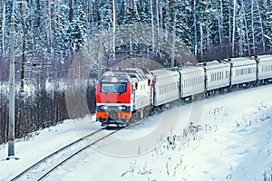 Passenger train approaches to the station at cold winter morning time.