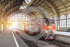 Passenger train with a diesel locomotive at the station under the roof