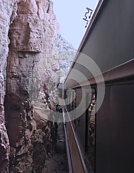 A Passenger Train Passes Inches from Towering Red Rock Walls