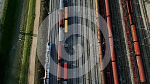 Passenger train passing by cargo trains parked at the station, drone view