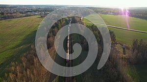 Passenger train on railway from forest, aerial view. Train with passenger cars rides along forests in spring.