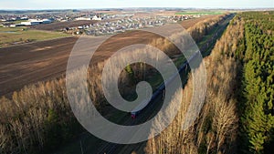 Passenger train on railway from forest, aerial view. Train with passenger cars rides along forests in spring.