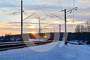 Passenger train rides by train at sunset, the sun`s rays of the sun