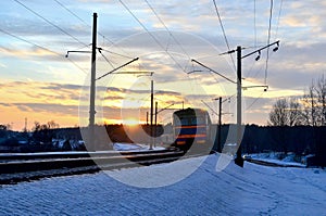 Passenger train rides by train at sunset, the sun`s rays of the sun