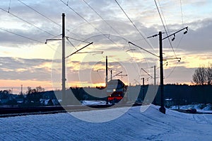 Passenger train rides by train at sunset, the sun`s rays of the sun in the winter