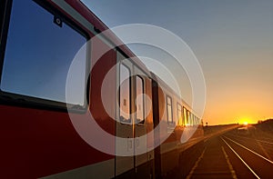 Passenger train stationed in a station in the middle of Carpathian mountains, Transylvania area, at sunset.