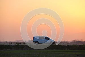 Passenger van driving fast on intercity road at sunset. Highway traffic in evening