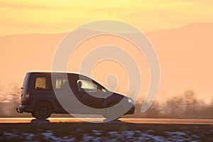 Passenger van driving fast on intercity road at sunset. Highway traffic in evening