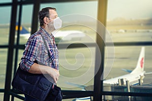 A passenger in a white medical mask ambles in the airport departure hall