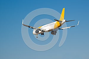 Passenger yellow and white colours airplane flying in the clear blue sky