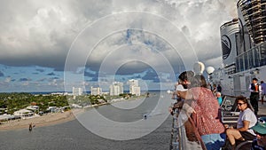 Passengers on  a cruise ship leaving Port Everglades, in Ft. Lauderdale, Florida look out over the ocean channel  with a luxury