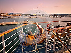 Passengers on a ferry relax on deck chairs while on holiday
