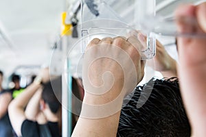 Passengers holding the hand rail on crowded public transports.