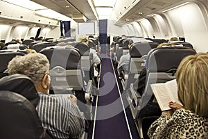 The passengers are reading in the cabin in flight.