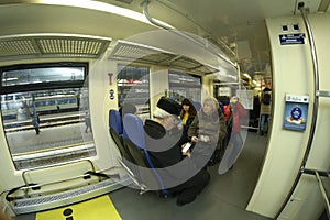 Passengers sitting on seats in the wagon of commuter train, waiting for departure, suitcases and bags put in the section for