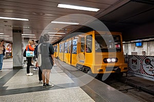 Passengers about to board yellow train wagons of Budapest subway