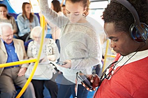 Passengers Using Mobile Devices On Bus Journey