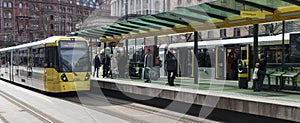 Passengers waiting for ariving tram on the platform at St Peters Square Station.  Public Transport Vehicle.  People in shot